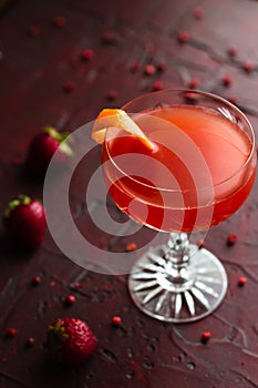 Gin cocktail in a coupe glass surrounded by strawberries