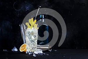 Gin mule cocktail with gin, lemon juice, soda and ginger. Black stone background, steel bar tools, copy space