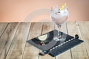 Gin Tonic with botanicals and bar spoon on wood table. photo