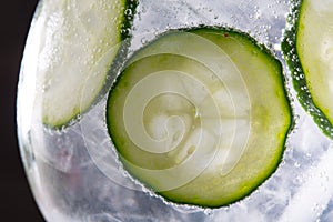 Gin tonic cocktail with cucumber and ice macro closeup