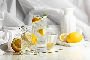 Gin-tonic cocktail with ice, rosemary and lemon slices on the white table