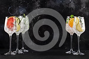 Gin and tonic cocktails set. Trendy Alcoholic drinks with lime, lemon, grapefruit, orange, cucumber, soda and spicy herbs in wine