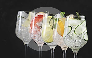 Gin tonic cocktails set in wine glasses. Trendy Alcoholic drinks with lime, lemon, grapefruit, orange, cucumber, soda and spicy