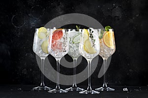 Gin tonic cocktails set in wine glasses. Trendy Alcoholic drinks with lime, lemon, grapefruit, orange, cucumber, soda and spicy