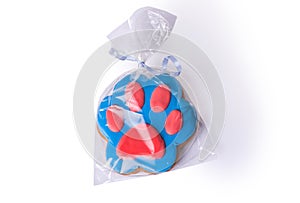 Ginderbread prepared in a shape of a dog paw covered with blue and red icing