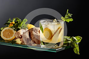 Ginger ale beer cocktail with lemon and mint in a frozen glass on a black background