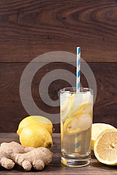 Ginger ale with lemon to accelerate metabolism. Refreshing healthful beverage. Wood background.