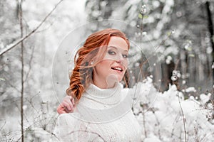 Ginger beautiful female in white sweater in winter forest. Snow december in park. Portrait. Christmas cute time.