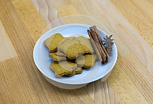 Ginger biscuits on a white plate with cinnamon sticks and aniseed