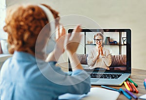 Ginger boy listening to friendly teacher and clap your hands during online lesson