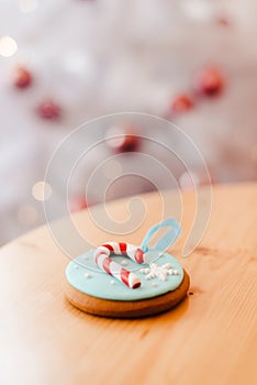 Ginger bread cookie on the table near the white Christmas tree with golden bokeh lights