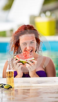 Ginger curly girl on piscine refreshing with watermelon