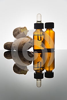 Ginger essential oil in amber bottle with ginger root and dropper