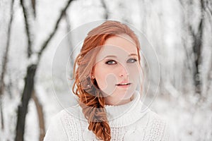 Ginger european girl in white sweater in winter forest. Snow december in park. Portrait. Christmas cute time.