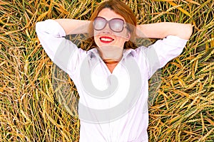 Ginger girl have a rest in a wheat field