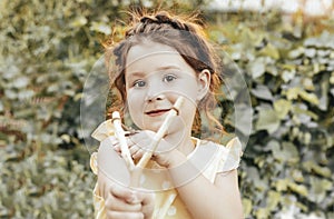 Ginger girl with slingshot in garden