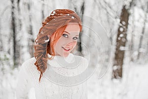 Ginger happy female in white sweater in winter forest. Snow december in park. Portrait. Christmas cute time.