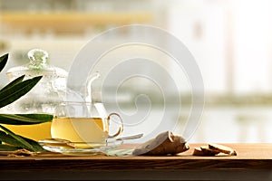 Ginger infusion on wooden kitchen bench with ginger root front