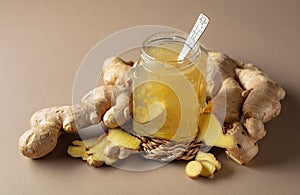 Ginger jam in small square jar and fresh ginger