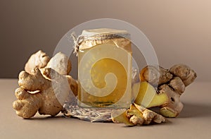 Ginger jam in small square jar and fresh ginger