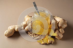 Ginger jam in small square jar and fresh ginger