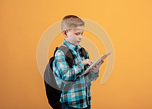 Ginger kid schooler using digital tablet on yellow