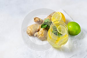 Ginger-lemon drink. Homemade Organic ginger in a glass with Lemon and mint on white table. Trendy detox healthy drink