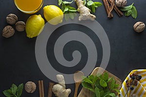 Ginger, lemons and mint leaves on dark background. Ginger tea, drink ingredients, cold and autumn time. Copy space