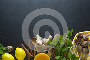 Ginger, lemons and mint leaves on dark background. Ginger tea, drink ingredients, cold and autumn time. Copy space