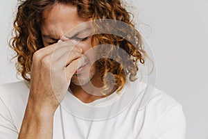 Ginger man with headache frowning and holding his nose bridge