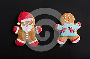 Ginger men with colored glaze on a black background . Gingerbread