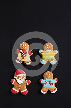 Ginger men with colored glaze on a black background . Gingerbread