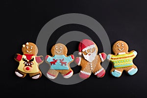 Ginger men with colored glaze on a black background . Gingerbread