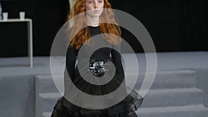 Ginger model walking on defile podium. Catwalk runway by redhead girl lace dress