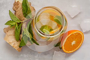 Ginger orange ice tea with mint in a glass jar, white background
