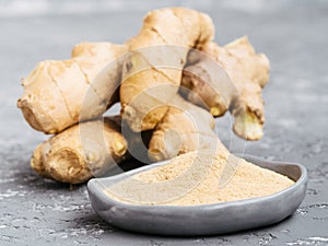 Ginger poder and ginger root on gray background photo