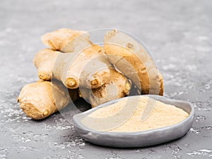 Ginger poder and ginger root on gray concrete background photo