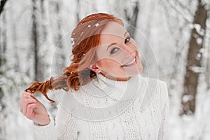 Ginger pretty girl in white sweater in winter forest. Snow december in park. Portrait. Christmas cute time.