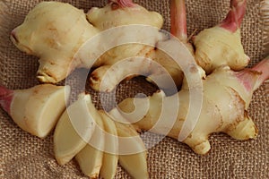 Ginger root and slices on wood background with cup of ginger tea. healthy drink.
