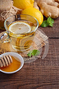 Ginger root tea with lemon and honey on wooden background