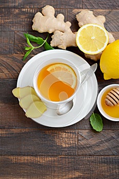 Ginger root tea with lemon and honey on wooden background.