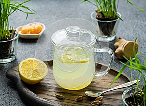 Ginger tea with lemon in a glass mug on a dark concrete background