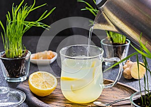 Ginger tea with lemon in a glass mug on a dark concrete background