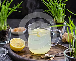 Ginger tea with lemon in a glass mug on a dark concrete background