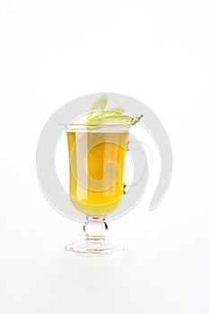 Ginger tea with lemon in a glass mug decorated with celery isolated on white background