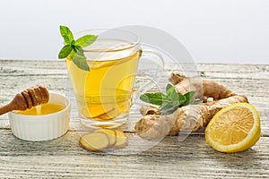 Ginger tea with lemon mint and honey on a white wooden background. Hot healthy winter drink