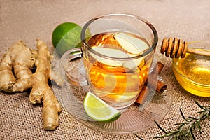 Ginger tea and lime on saucer with raw ginger and honey in the b