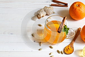 Ginger tea with saffron in a glass Cup, decorated with mint and cinnamon on a light background with space