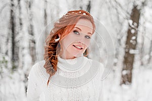 Ginger tender girl in white sweater in winter forest. Snow december in park. Christmas time.