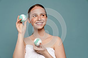 Ginger woman wearing towel smiling while showing balls bath bomb